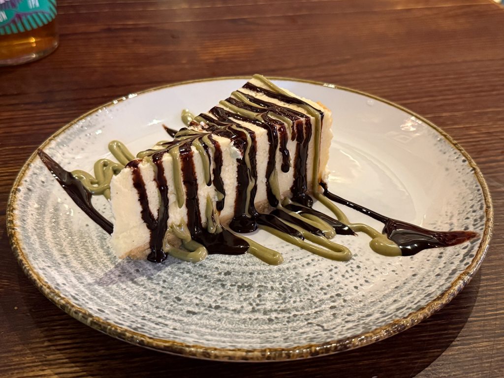 Optional als Dessert: ein "Baked Vanilla Cheescake - mit PIstazie- und Schokoladensoße garniert (2026)