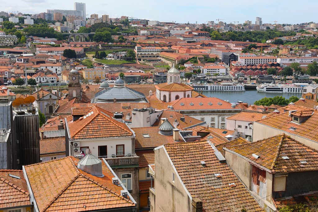 In Porto man blickt von oben auf bunte Hausfassaden, rote Ziegeldächer, die geschwungenen Brücken und den glitzernden Fluss darunter, fast wie auf eine liebevoll gestaltete Modelllandschaft. Foto: Hans-Martin Goede